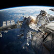 Deux astronautes en combinaison spatiale travaillant à l'extérieur de la Station spatiale internationale, la Terre en fond.